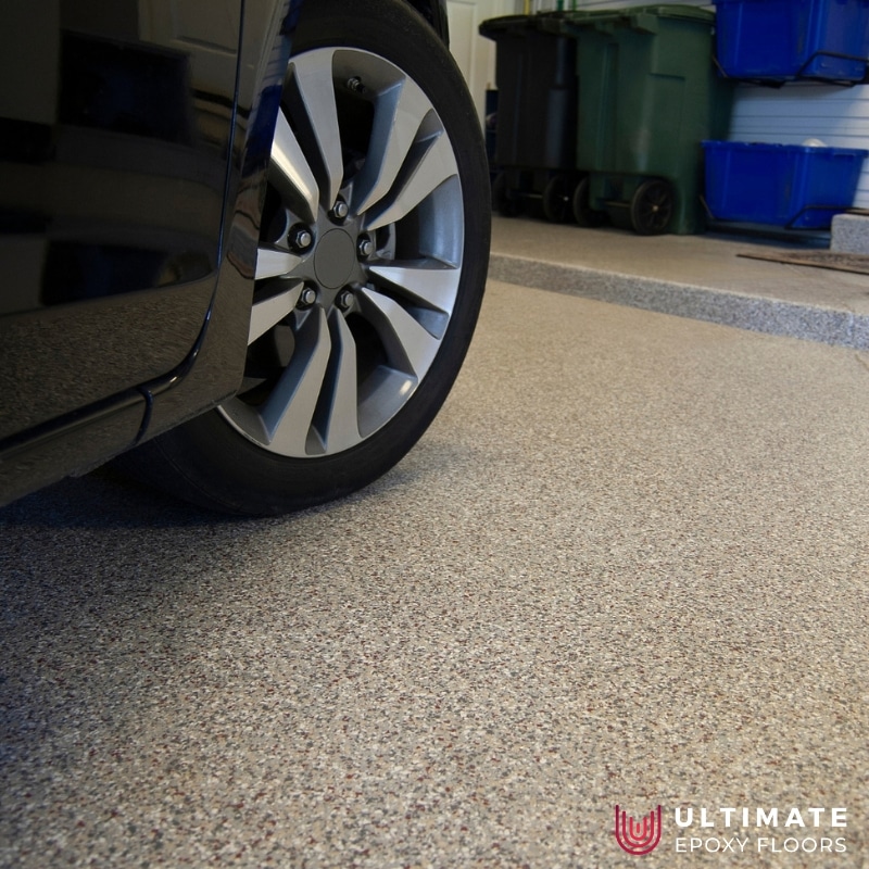 A sleek, glossy garage epoxy floors with gray decorative chips providing a stylish and durable upgrade for your garage