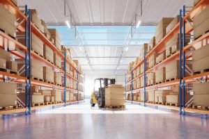 Industrial warehouse with sturdy epoxy flooring for industrial use, featuring organised shelves filled with boxes and a forklift handling heavy loads. The image demonstrates the durability and suitability of epoxy flooring for environments with heavy machinery and forklifts.