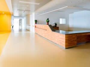 Spacious modern lobby with wooden reception desk and epoxy outdoor flooring, showcasing its clean look and impact on indoor air quality.