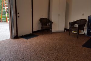 Interior of a garage with customisable epoxy flake floor colours in a warm brown tone, complementing chairs and storage cabinets.