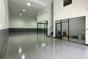 modern commercial space with smooth grey interior epoxy flooring, glass office partition, and high ceilings for a professional look