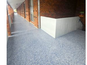 Polished concrete flooring in a long hallway with brick walls, showcasing a durable and sleek finish.