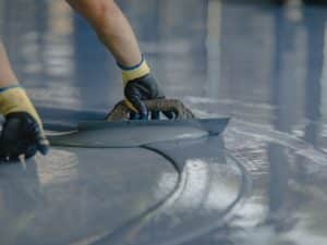 a professional applying a epoxy flooring for a good epoxly floor lifespan