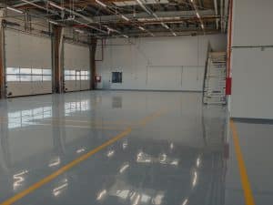 A well-lit workshop showcasing various types of epoxy flooring, including metallic, flake, and solid colour options.