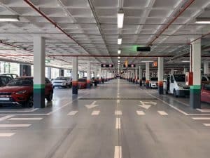 Spacious car park featuring epoxy flooring, clear markings, parked vehicles, and lighting for efficient traffic flow.