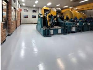 Factory interior with heavy machinery installed over a white epoxy concrete floor designed for industrial durability.