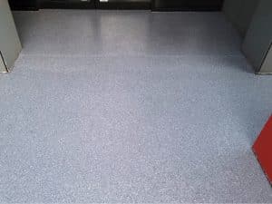 Close-up of seamless flake epoxy art gallery flooring in a modern interior with a smooth, slip-resistant grey finish.
