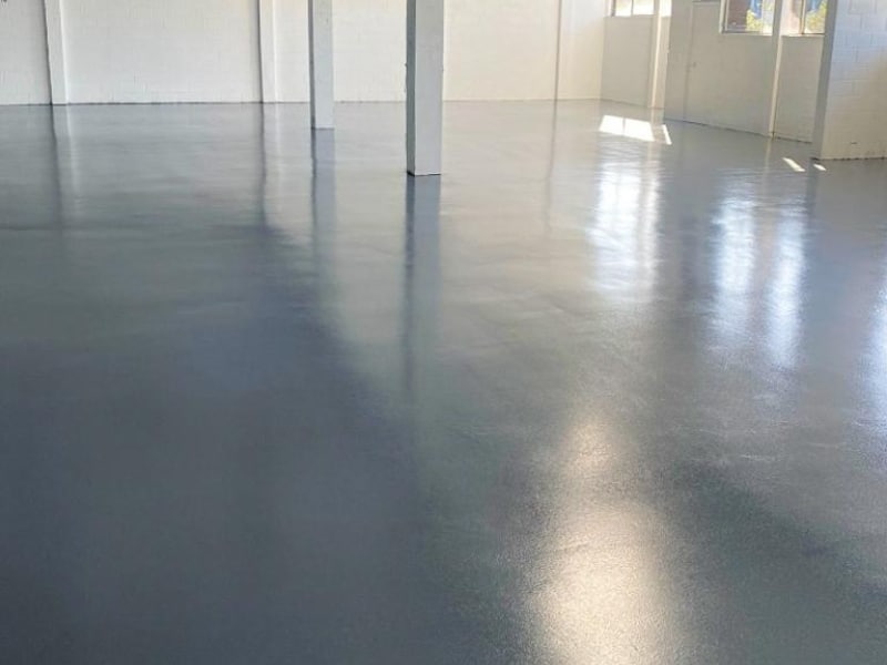 Smooth warehouse surface after epoxy floor application showing glossy grey coating.